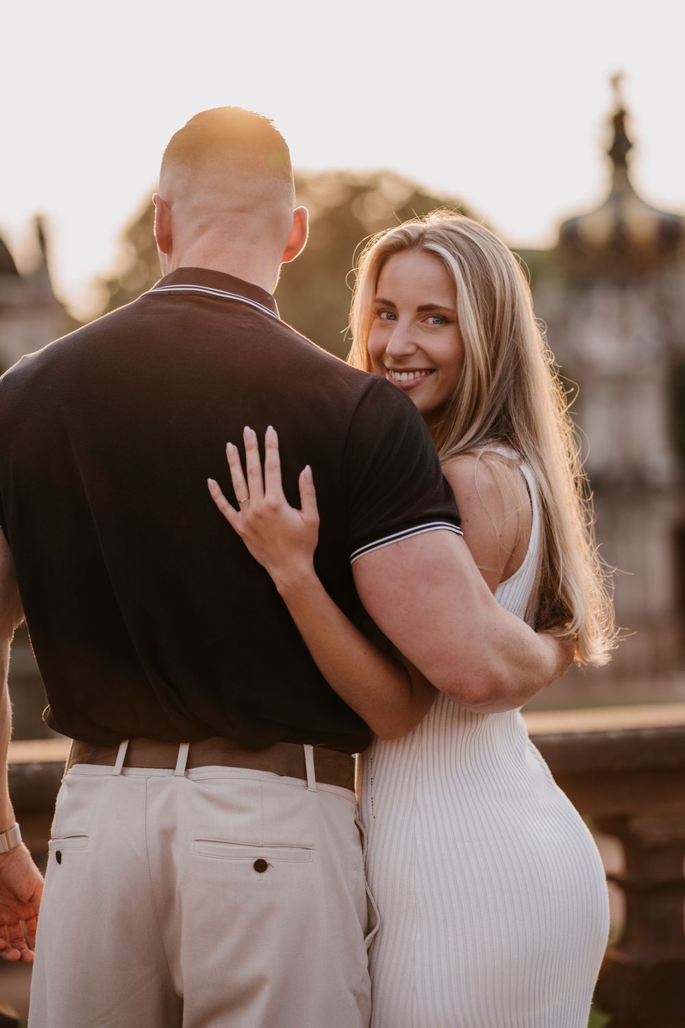 Romantic couple embraces during golden hour sunset photoshoot in urban setting.