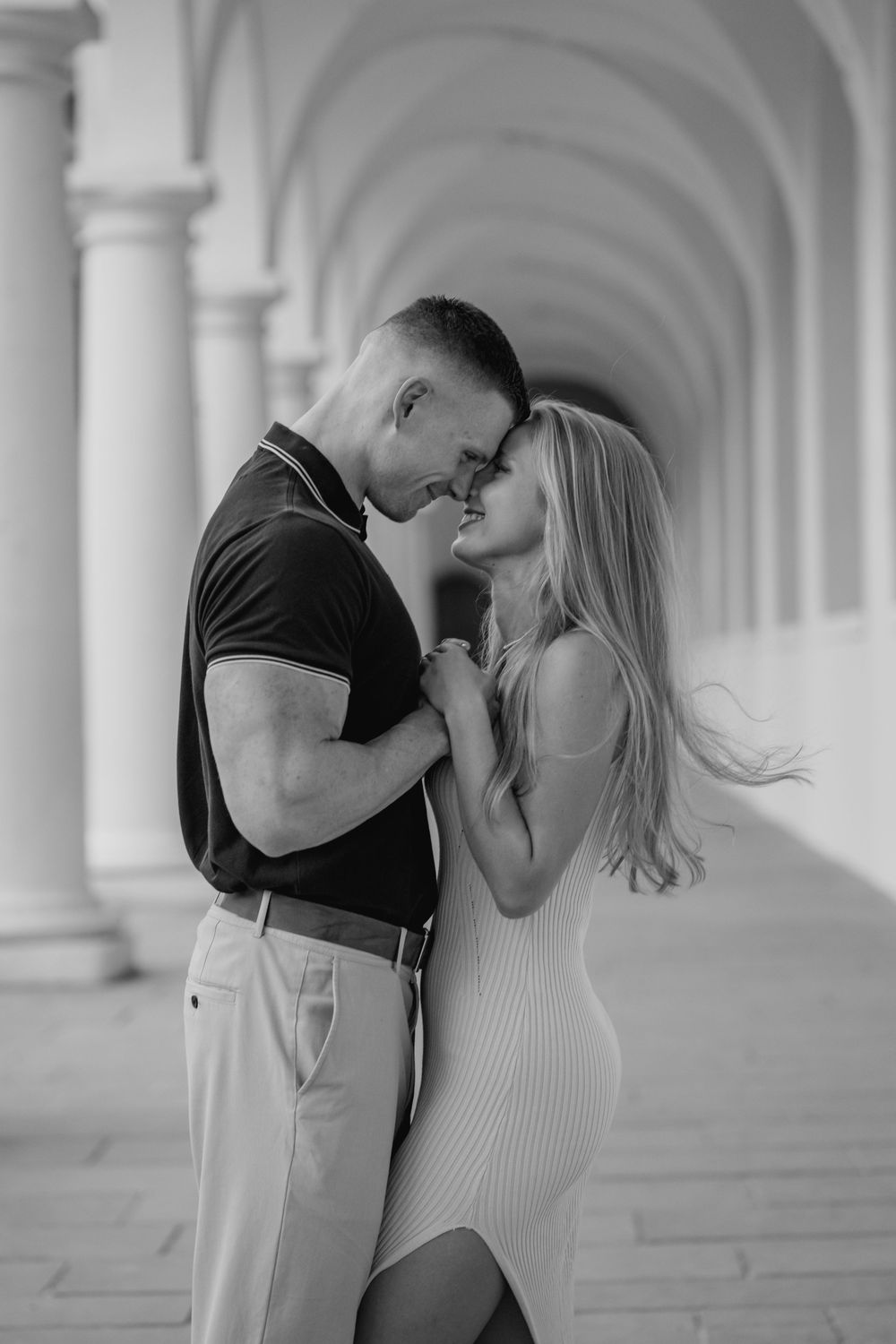 A romantic black and white photo series showing a couple sharing intimate moments in an elegant columned hallway.