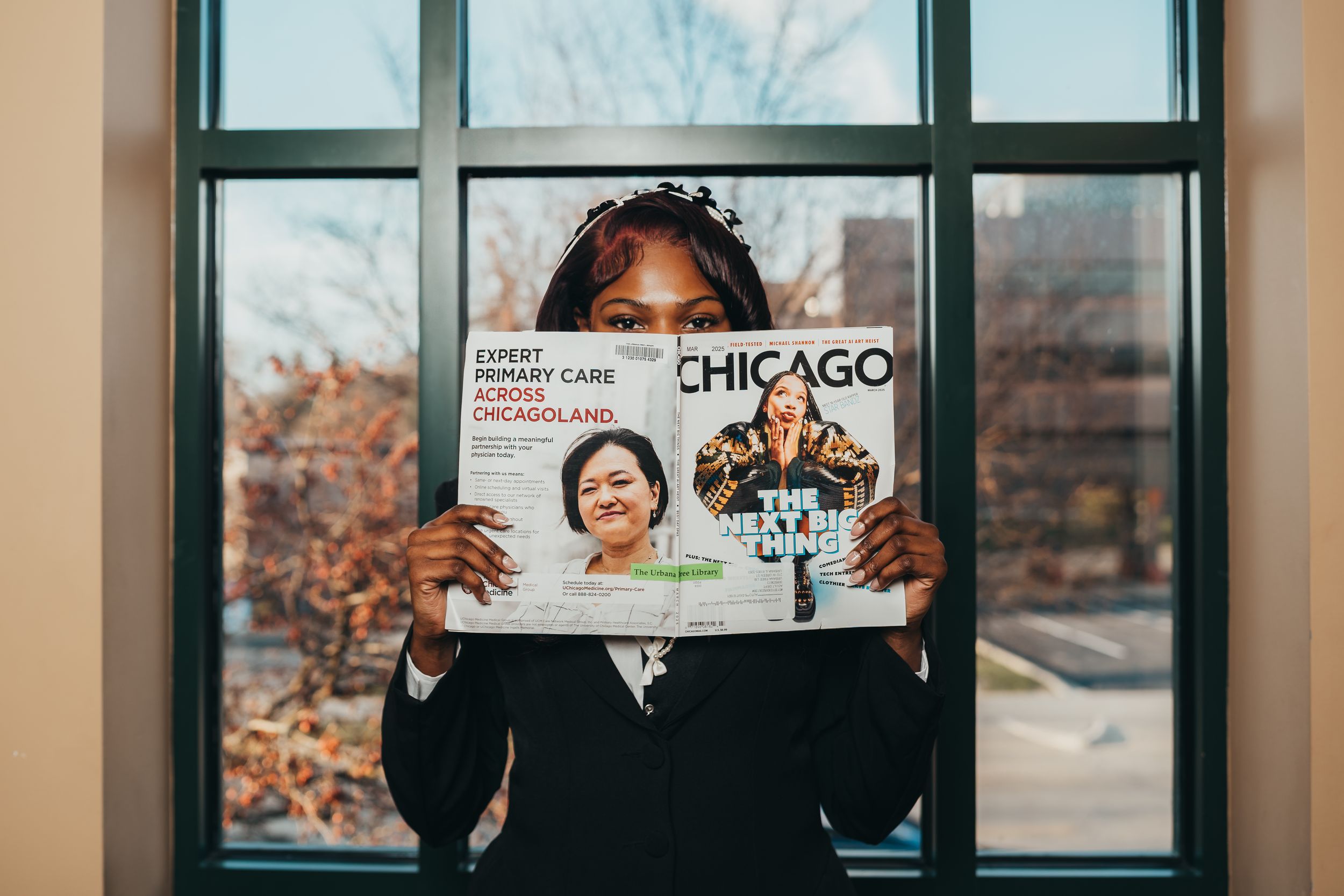 Someone holding up a Chicago magazine cover near a window.