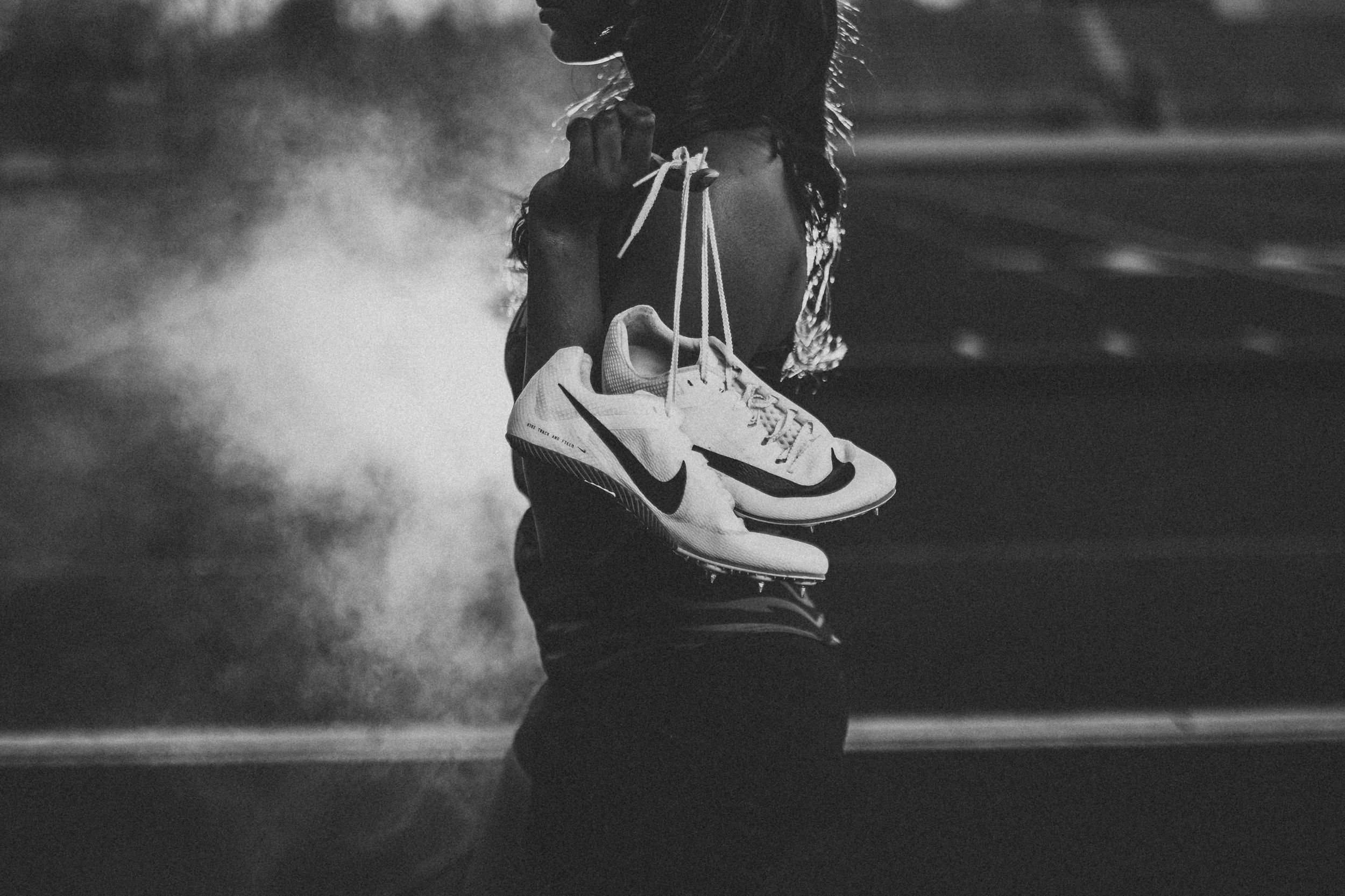 A pair of sneakers hanging by their laces in a moody black and white street scene with smoke.
