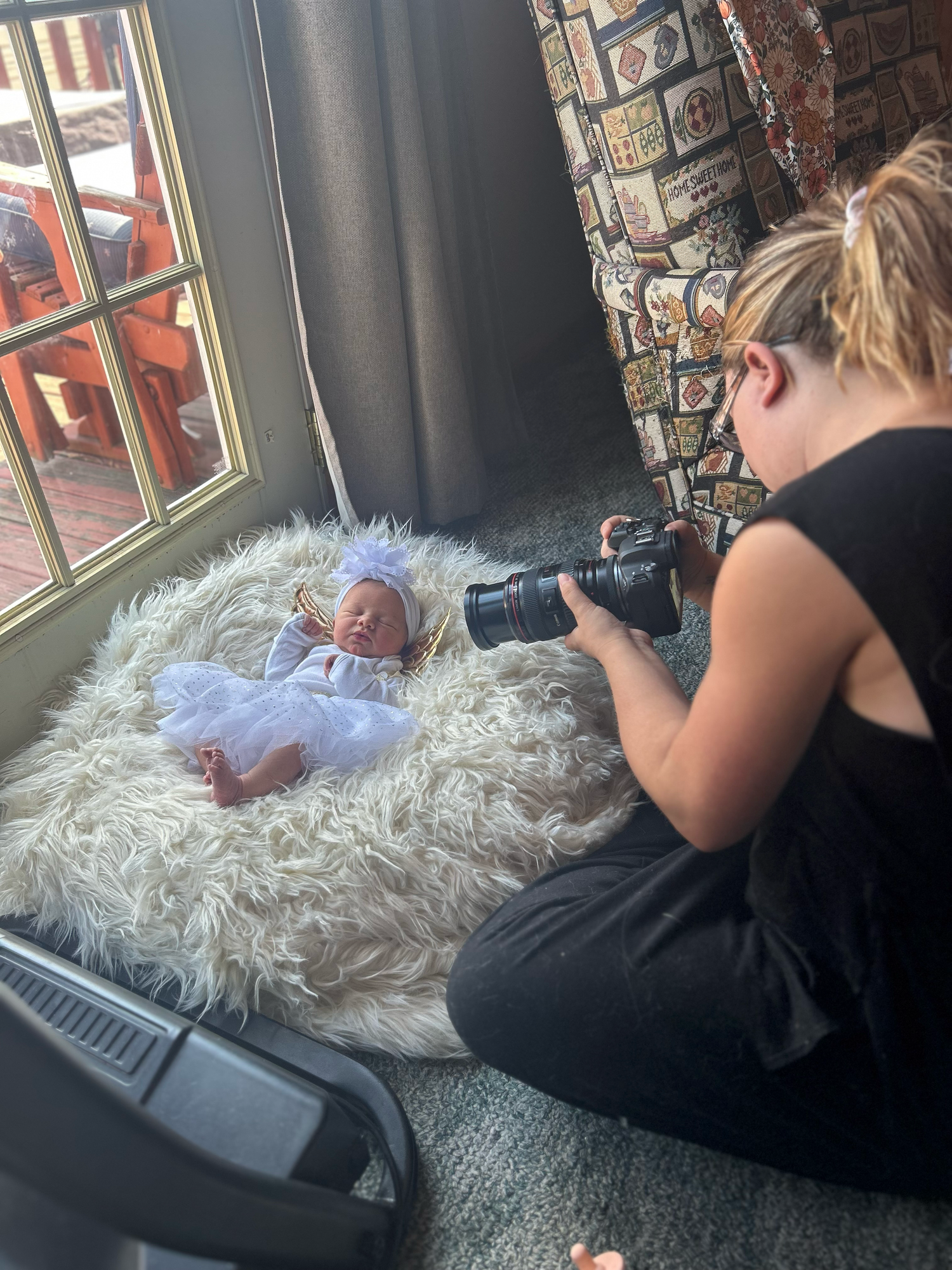 Person relaxing on fluffy white carpet while reading near window.