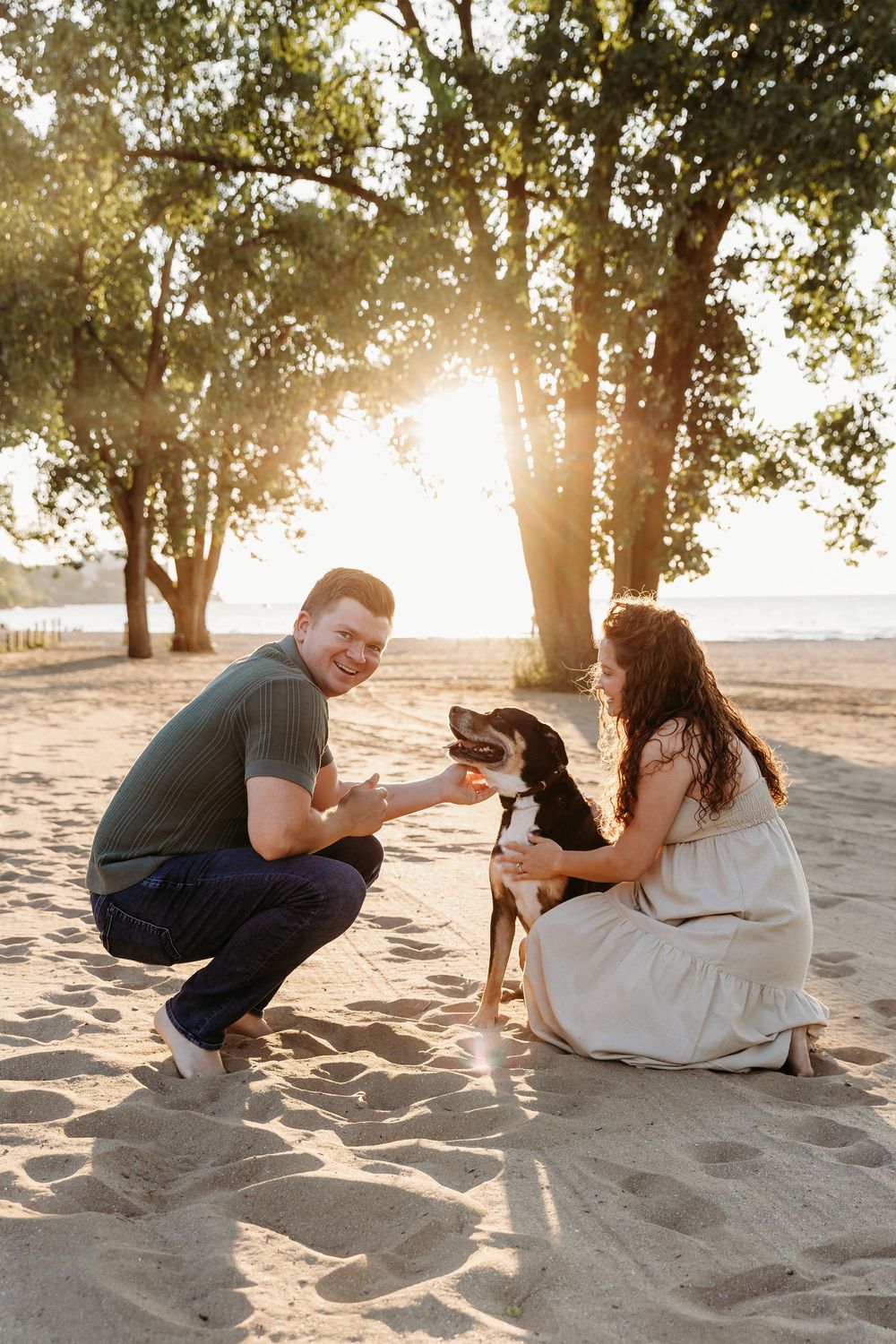 A couple sits together on a sandy beach at sunset while surrounded by trees casting long shadows. Cleveland Maternity Photographer