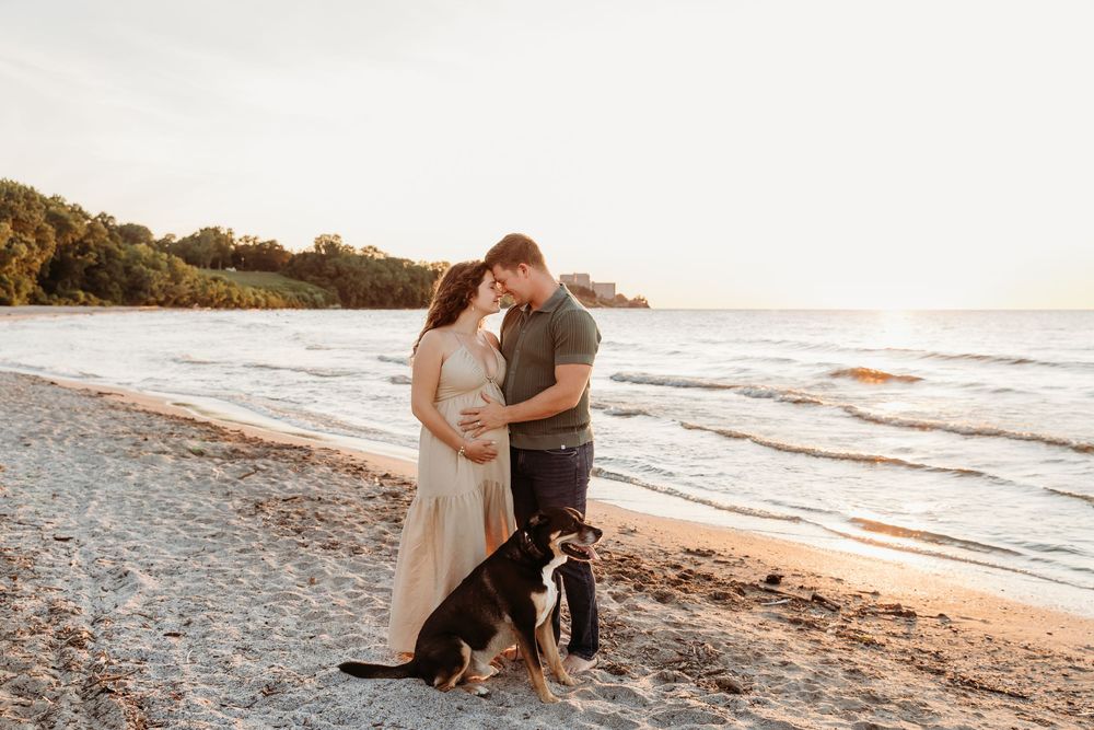 Couple embraces on sandy beach at sunset while waves crash on the shore in romantic seaside moment.