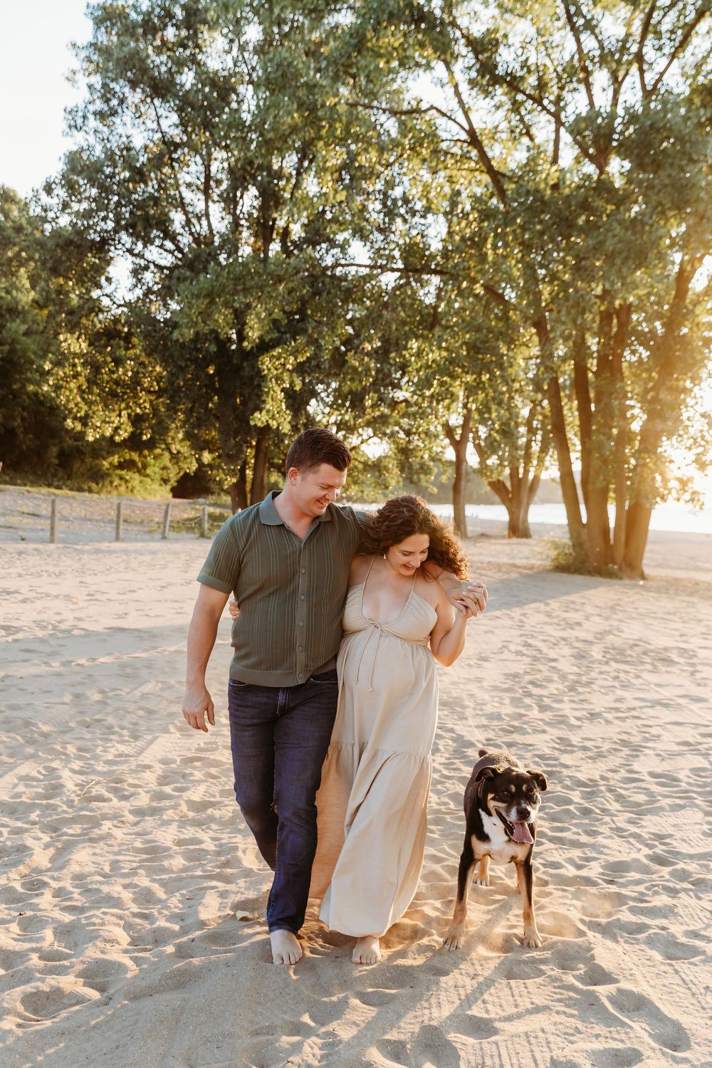 Couple enjoying a sunset moment on the beach with their black dog beside them. Cleveland Maternity Photographer