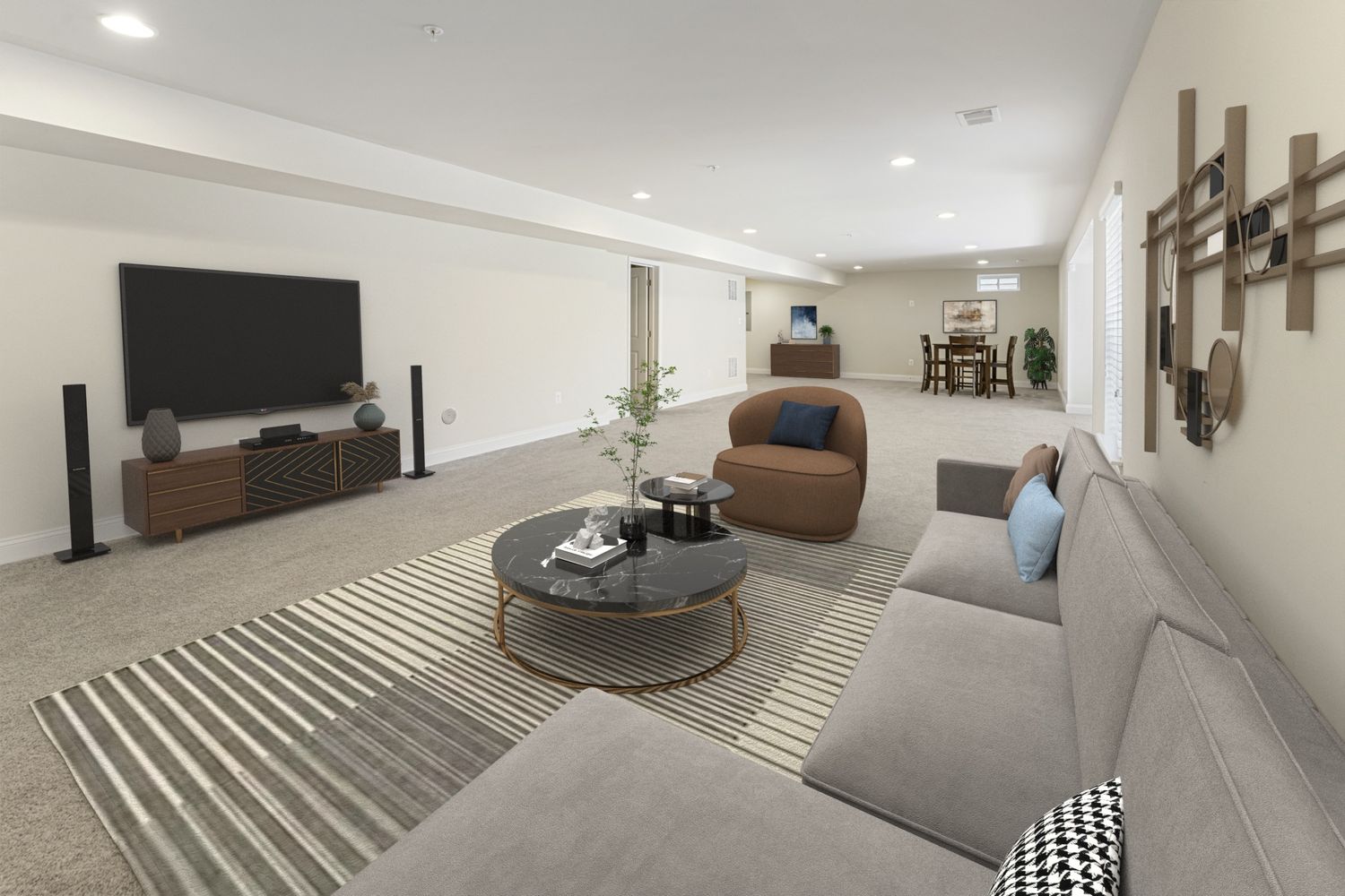 Modern basement living area with grey sectional sofa, round coffee table, and recessed lighting.