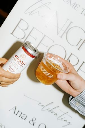 Hand holding a glass of golden beer or ale against a white background with text.