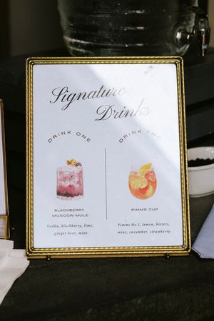Close-up view of elegant drink menu cards displaying signature cocktail illustrations and names on black background.