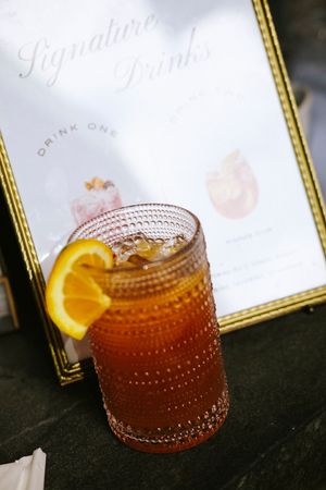 A sequence of five photos showing a cocktail being poured into a textured glass with an orange garnish.