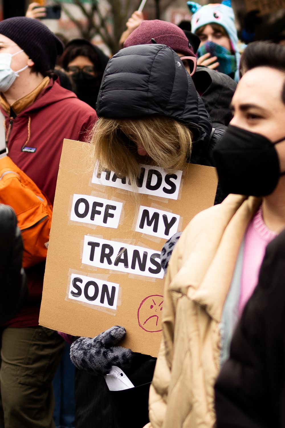 Queer liberation march attendee holds a sign supporting their trans son taken by lesbian photographer Kade Joy.