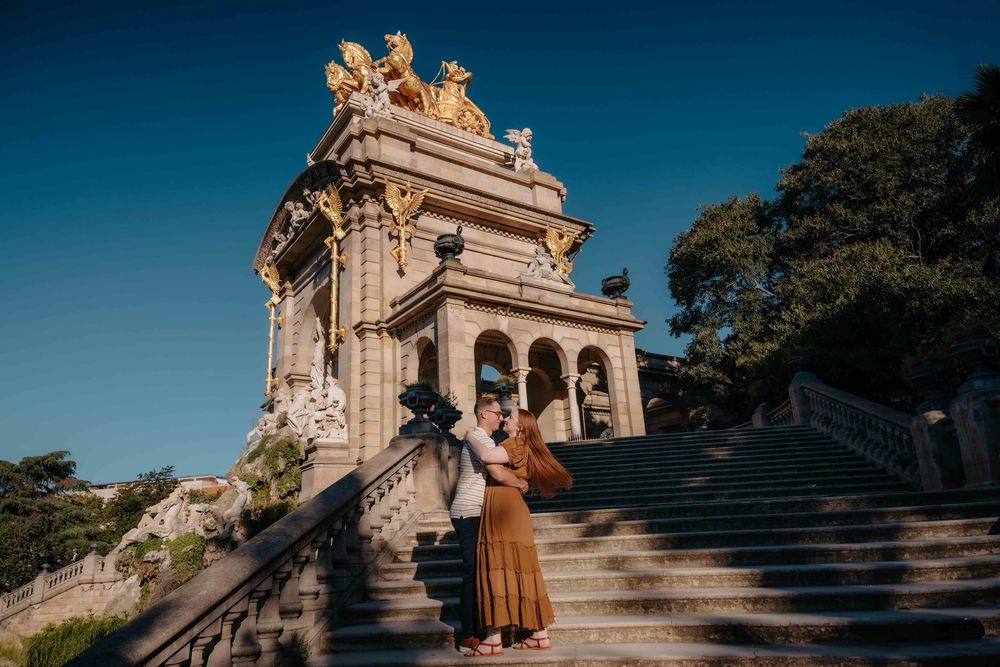 Elegant couple holding hands walking down Ciutadella Park avenue September morning.