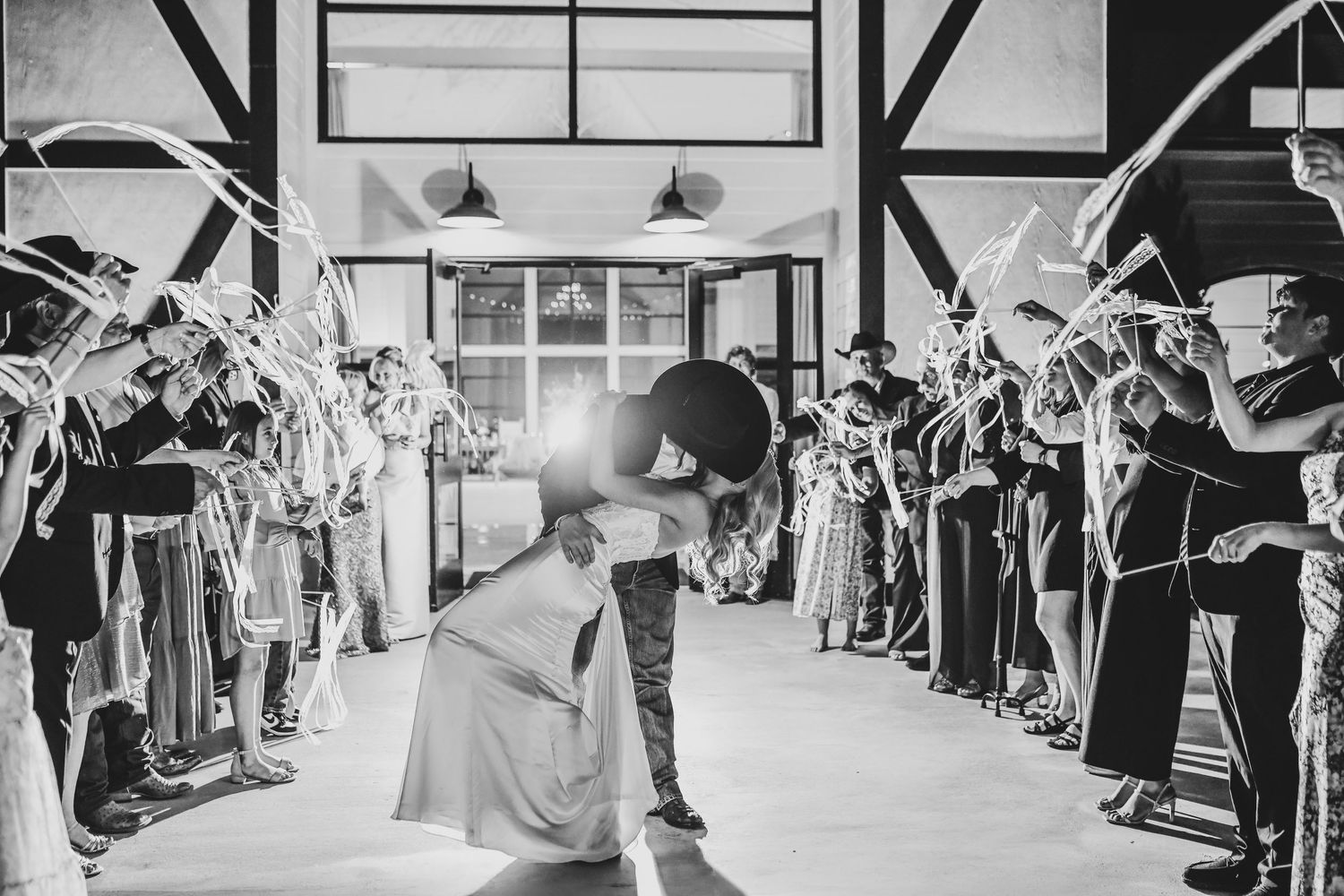 Bride and groom share a romantic dip kiss during ribbon exit at The Gardenia wedding venue in Valley View Texas