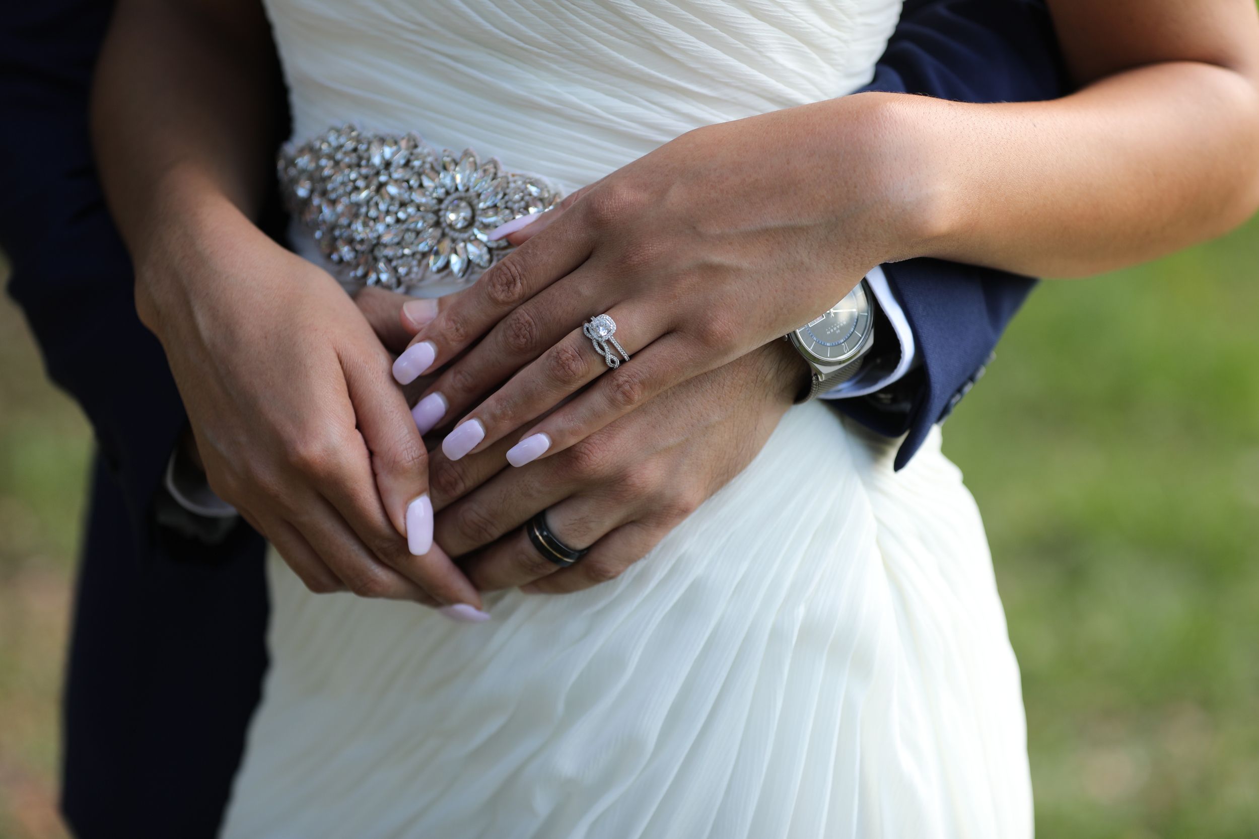 Close-up of wedding rings and embellished dress detail.