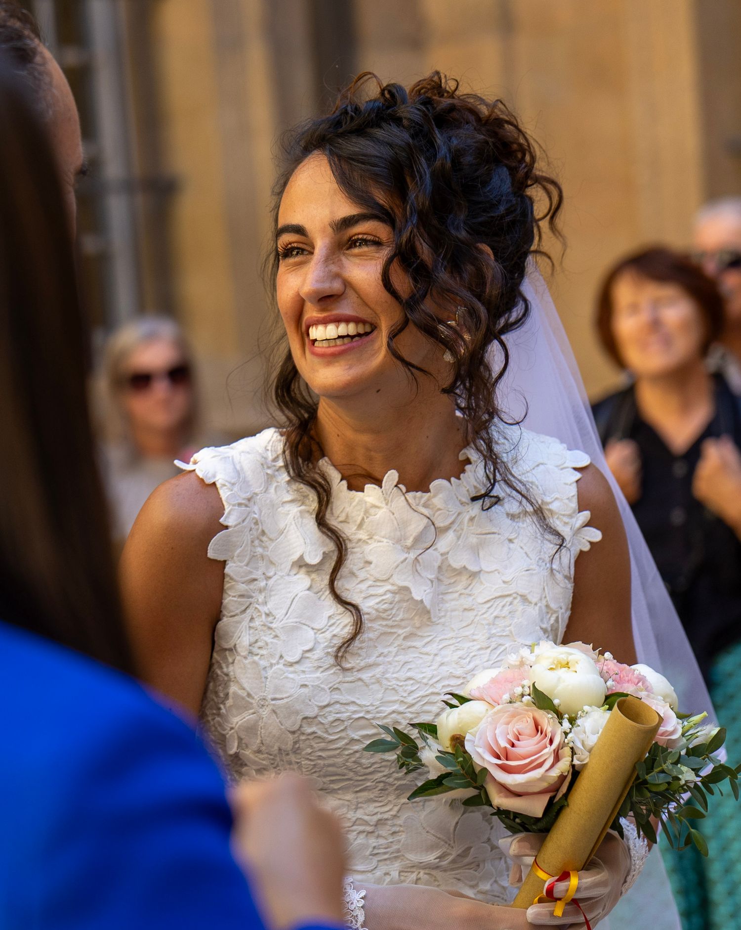 La mariée sourit pendant la cérémonie, son bouquet à la main