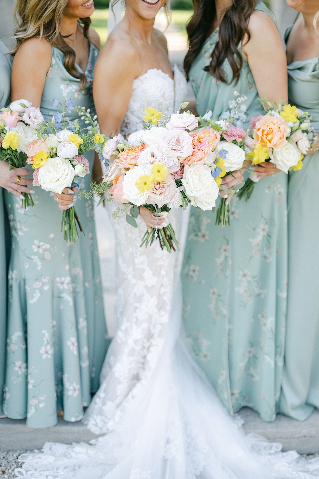 Armour House Wedding - Bride in lace gown holds colorful bouquet flanked by bridesmaids in sage green floral dresses at wedding.