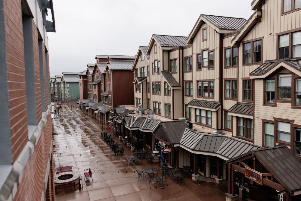 Rainy day view of a modern mountain town shopping district with wet brick walkways and peaked roof architecture.