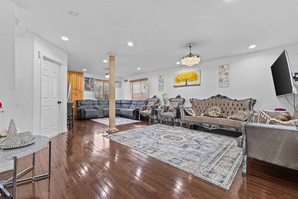 Elegant living room with hardwood floors, decorative column, recessed lighting, and ornate upholstered furniture.