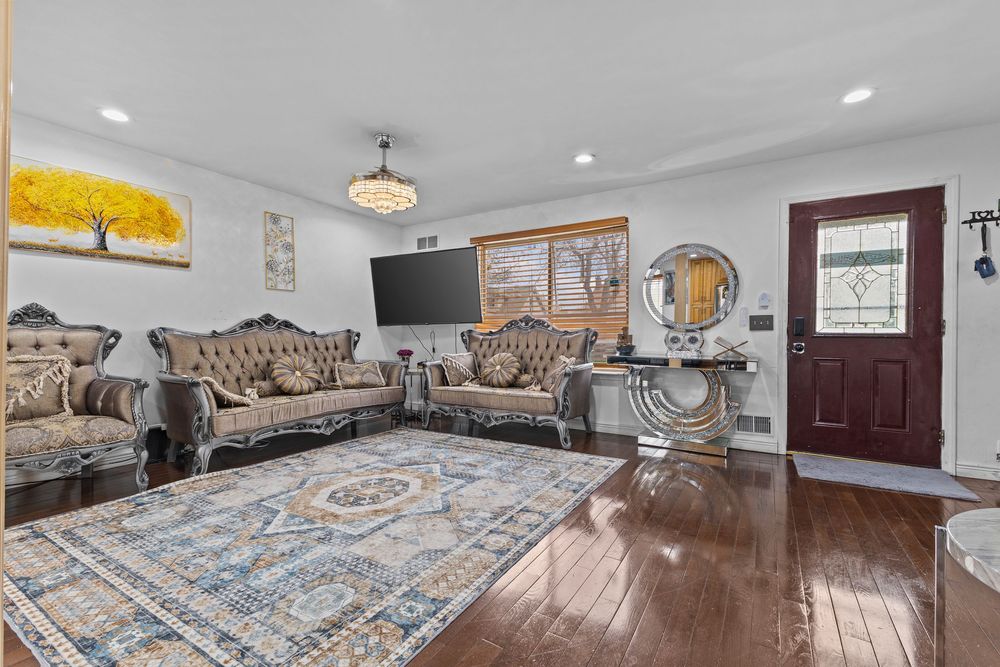 Elegant living room with ornate tufted sofas, Persian rug, hardwood floors, and decorative wall art.
