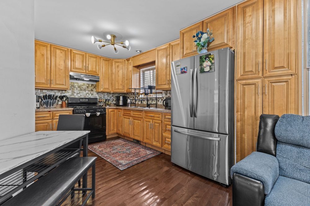 Spacious kitchen featuring oak cabinetry, stainless steel appliances, tile backsplash, and hardwood floors.