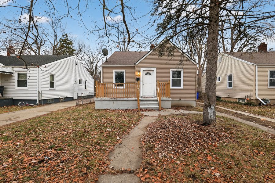 Charming bungalow home with brick facade, white trim, and mature trees in a residential neighborhood.