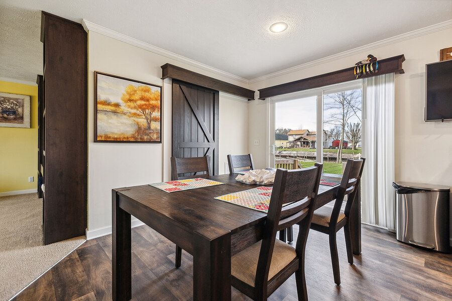 Dining area with dark wood table and chairs, sliding glass door, hardwood floors, and decorative barn door accent.