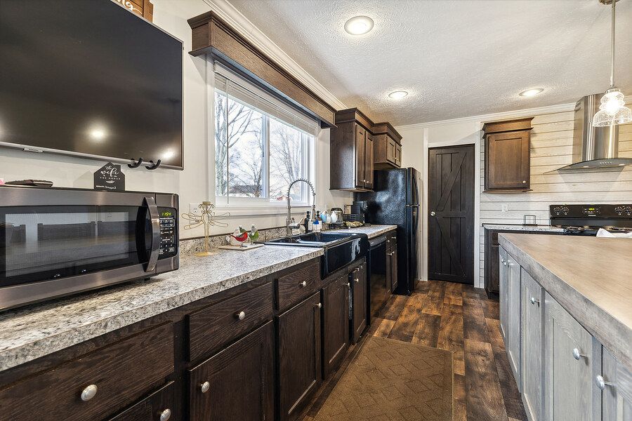 Modern kitchen with dark wood cabinets, granite countertops, stainless appliances, and hardwood floors.
