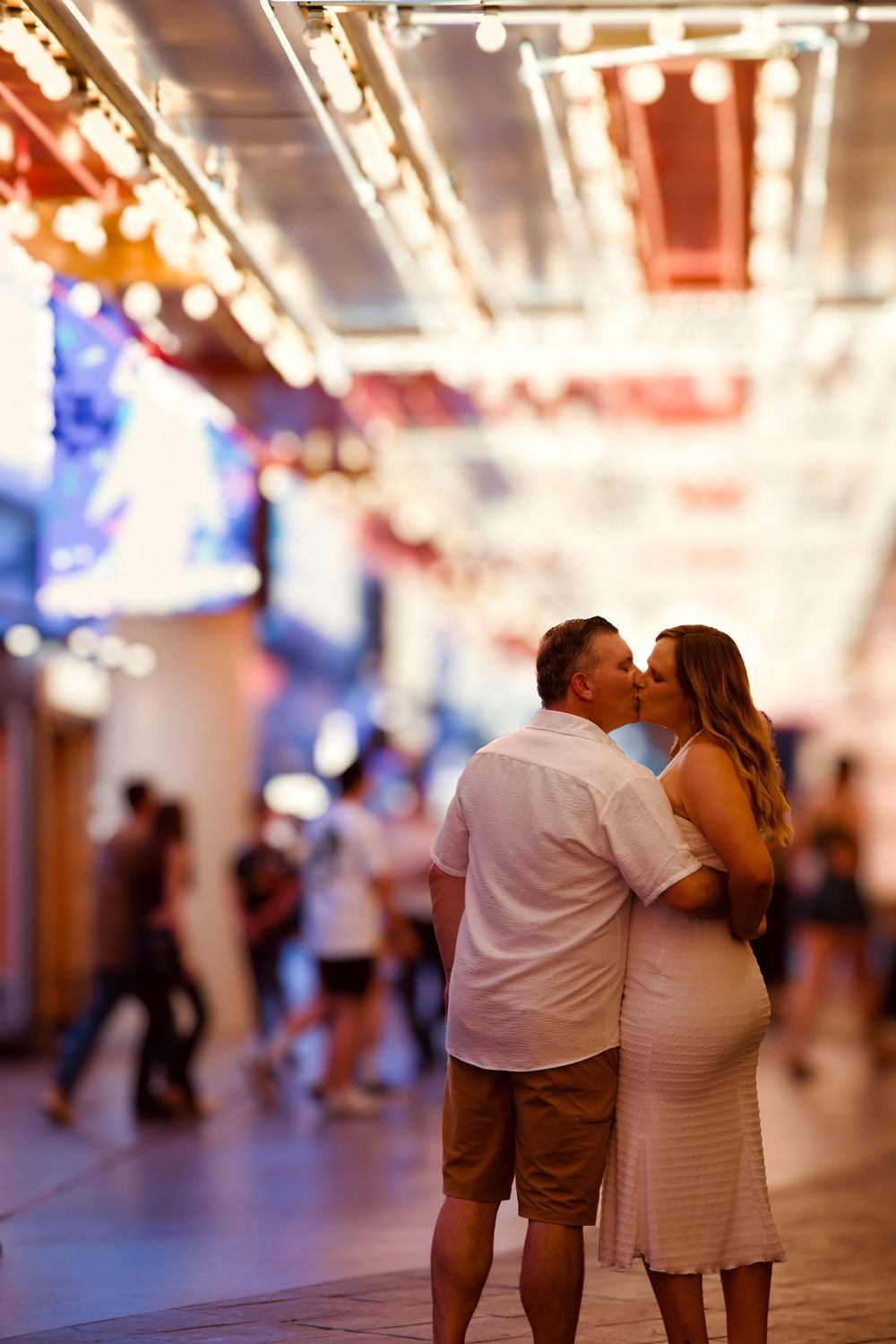 Couple sharing a romantic kiss under glowing string lights at the vibrant Fremont Street Experience in Las Vegas.
