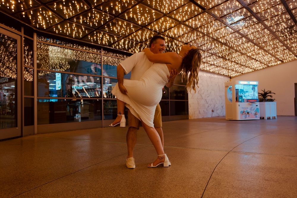 Couple sharing a romantic dip dance under sparkling lights at a wedding reception venue.