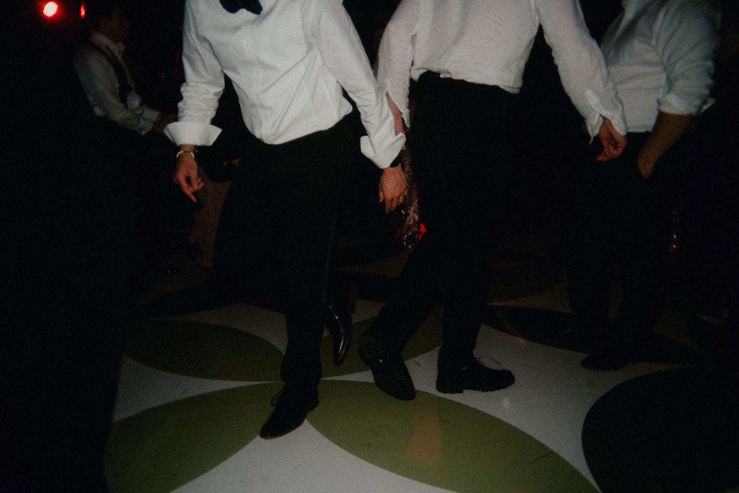 Men in formal tuxedos dancing on a decorative dance floor at an elegant evening event.