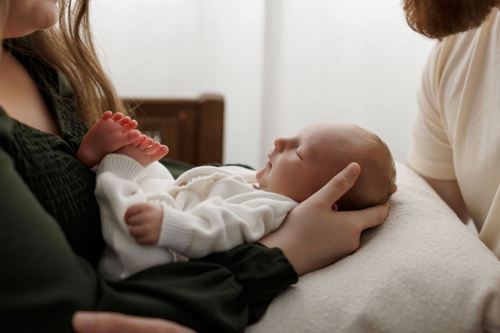 Newborn baby sleeping peacefully in parent's arms during a tender family moment.