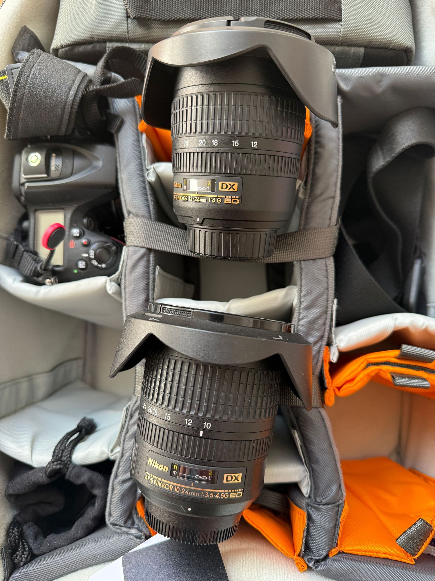 Two Nikon DX zoom lenses stored in padded camera bag compartments.