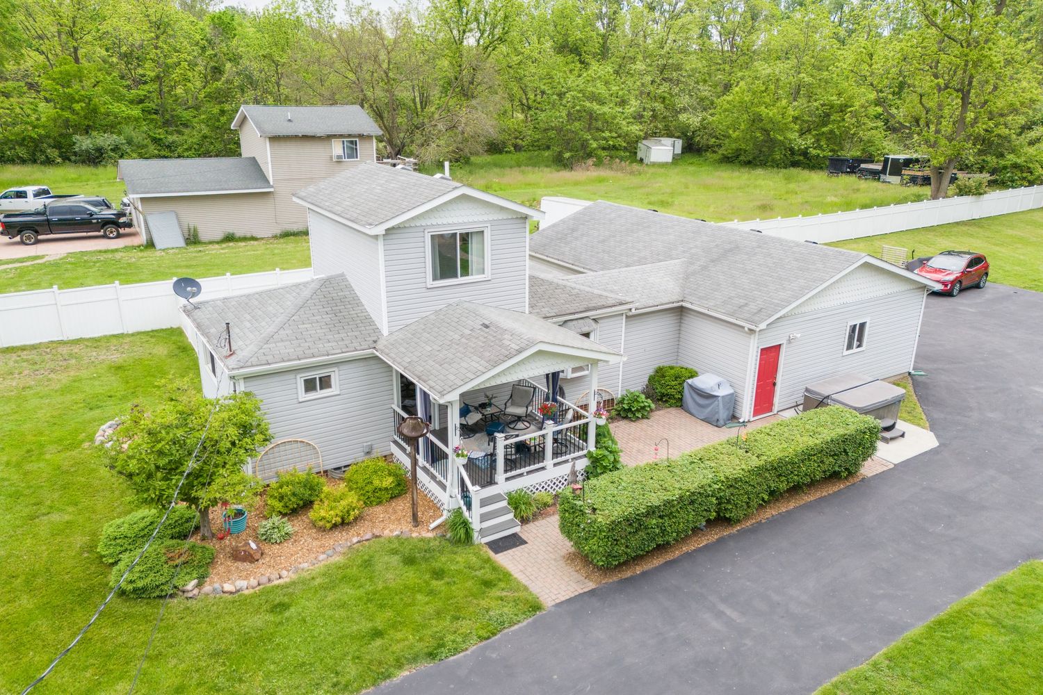 Brick ranch home with covered front porch, green lawn, and mature shade trees lining the property.