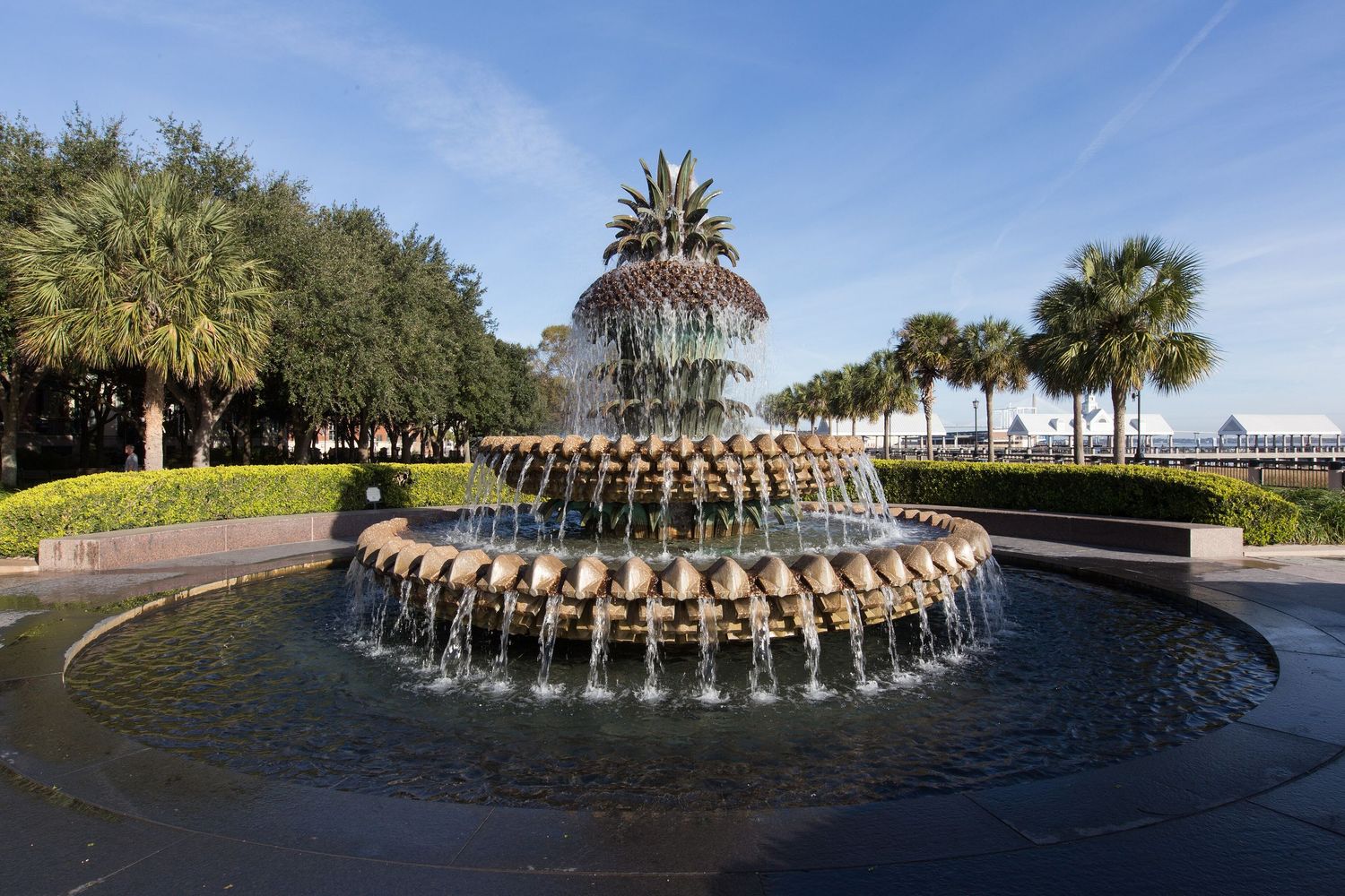 Iconic pineapple fountain with tiered water jets surrounded by palm trees in Waterfront Park, Charleston, SC.