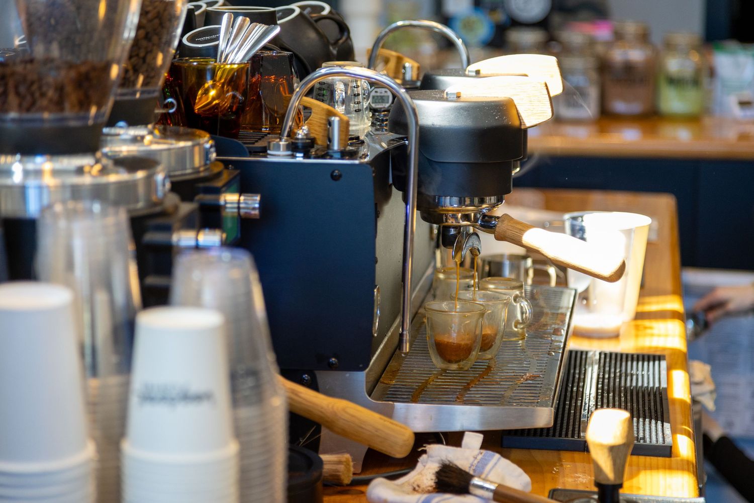 Close-up of professional coffee equipment and supplies arranged on a counter in a cafe setting.