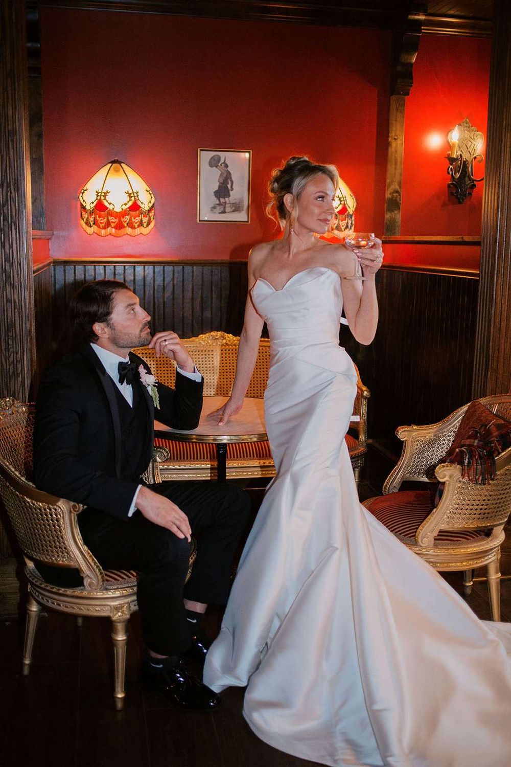 Estate Washington Wedding open house - bride and groom lounge in the bar area in front of a red wall and moody light fixtures.
