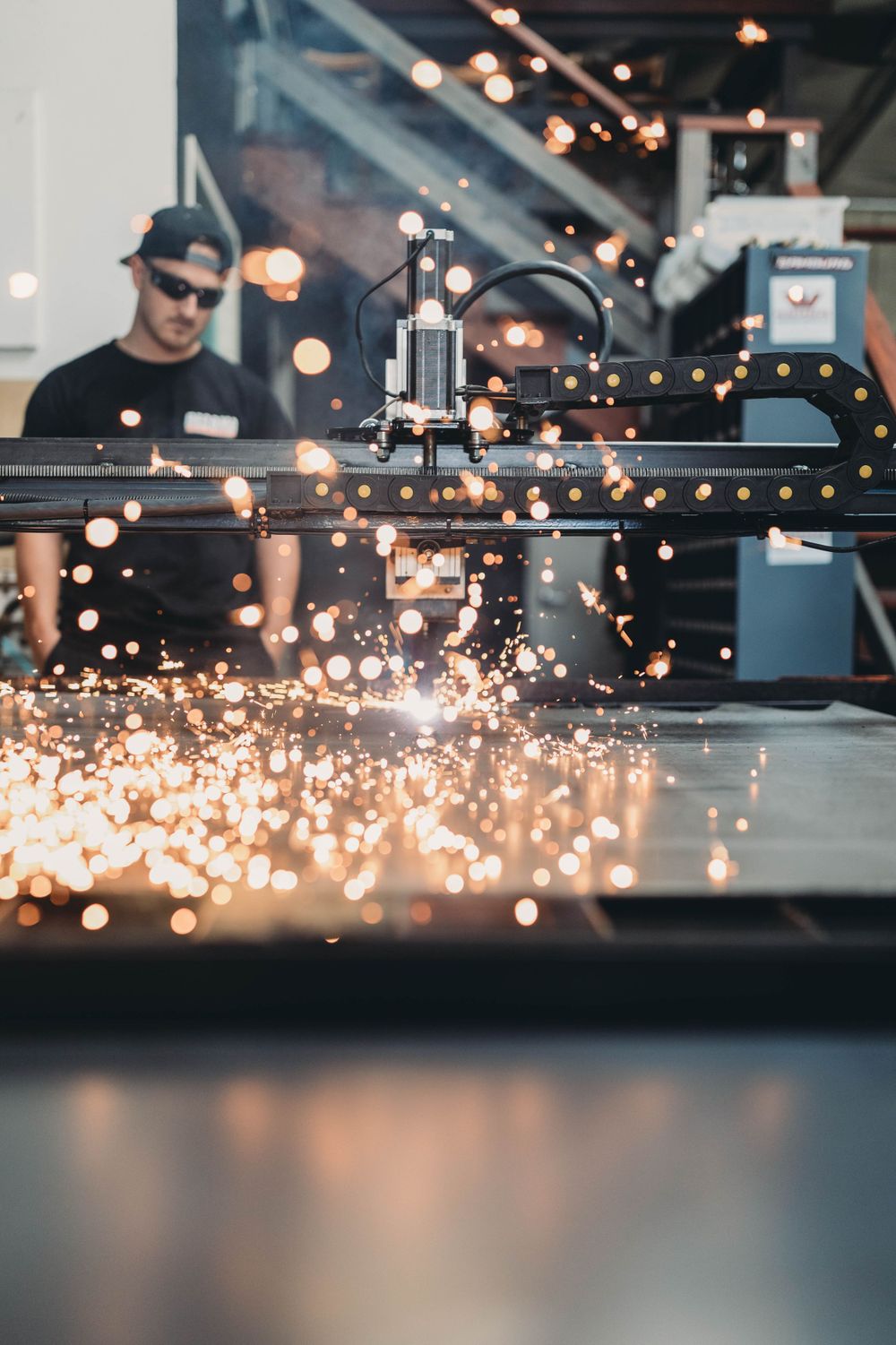 Sparks flying from industrial machinery in a workshop with bokeh lighting effects.