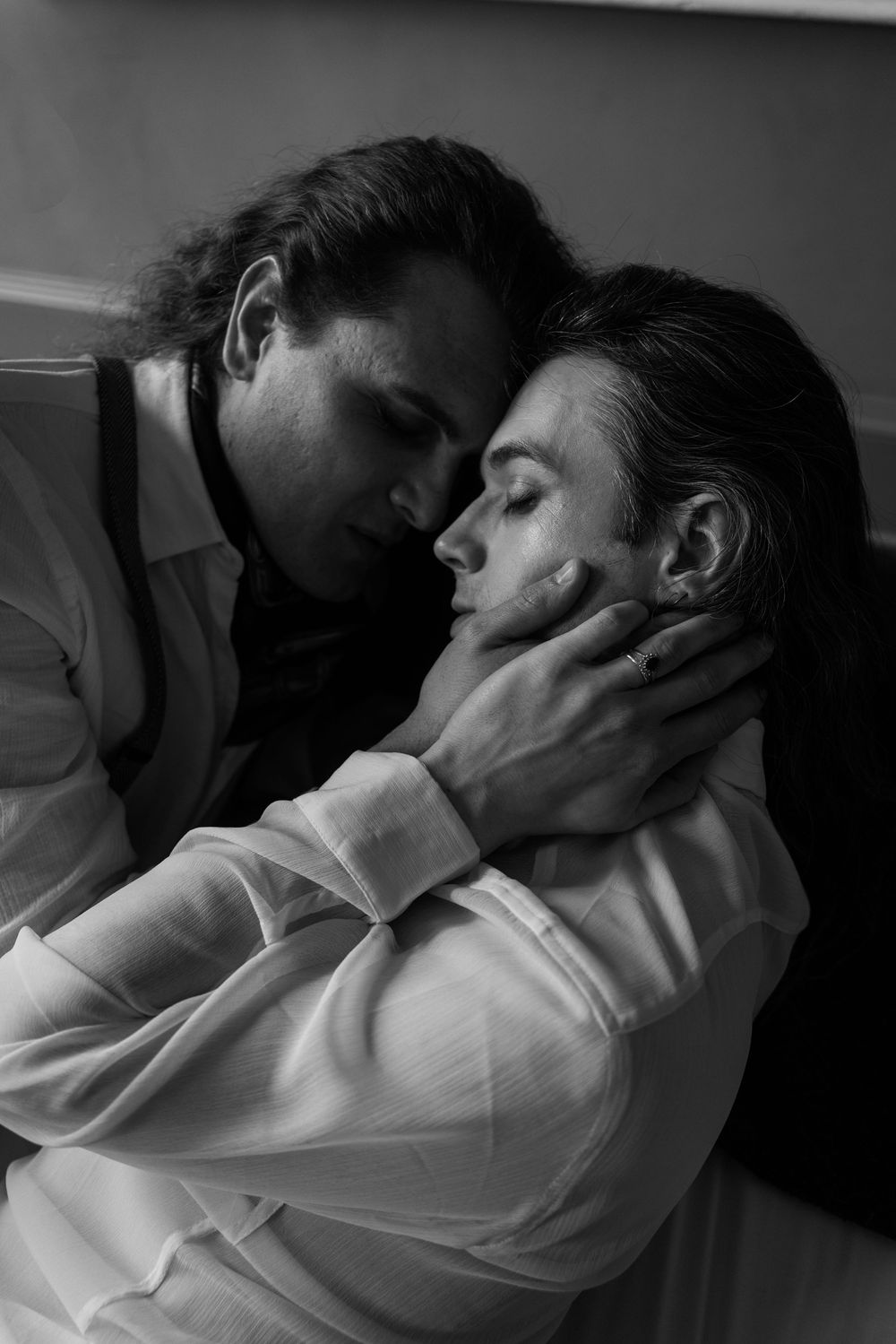 Black and white photo of two people in an intimate embrace, one cradling the other's face tenderly.