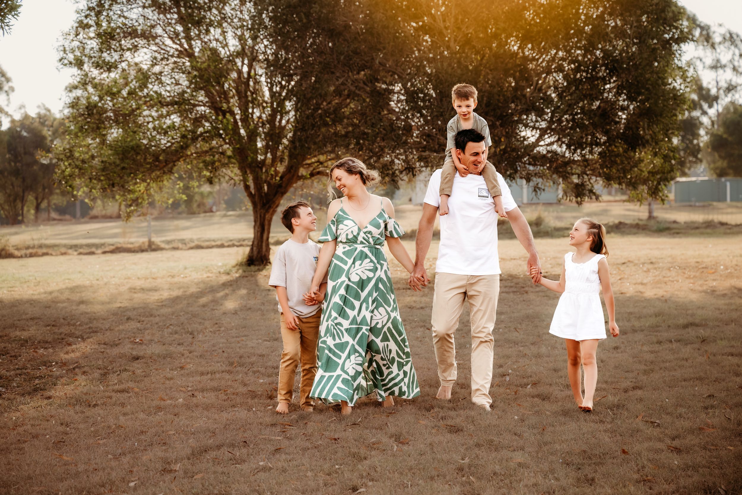 A group of people walk and play together in a sun-drenched field during golden hour.