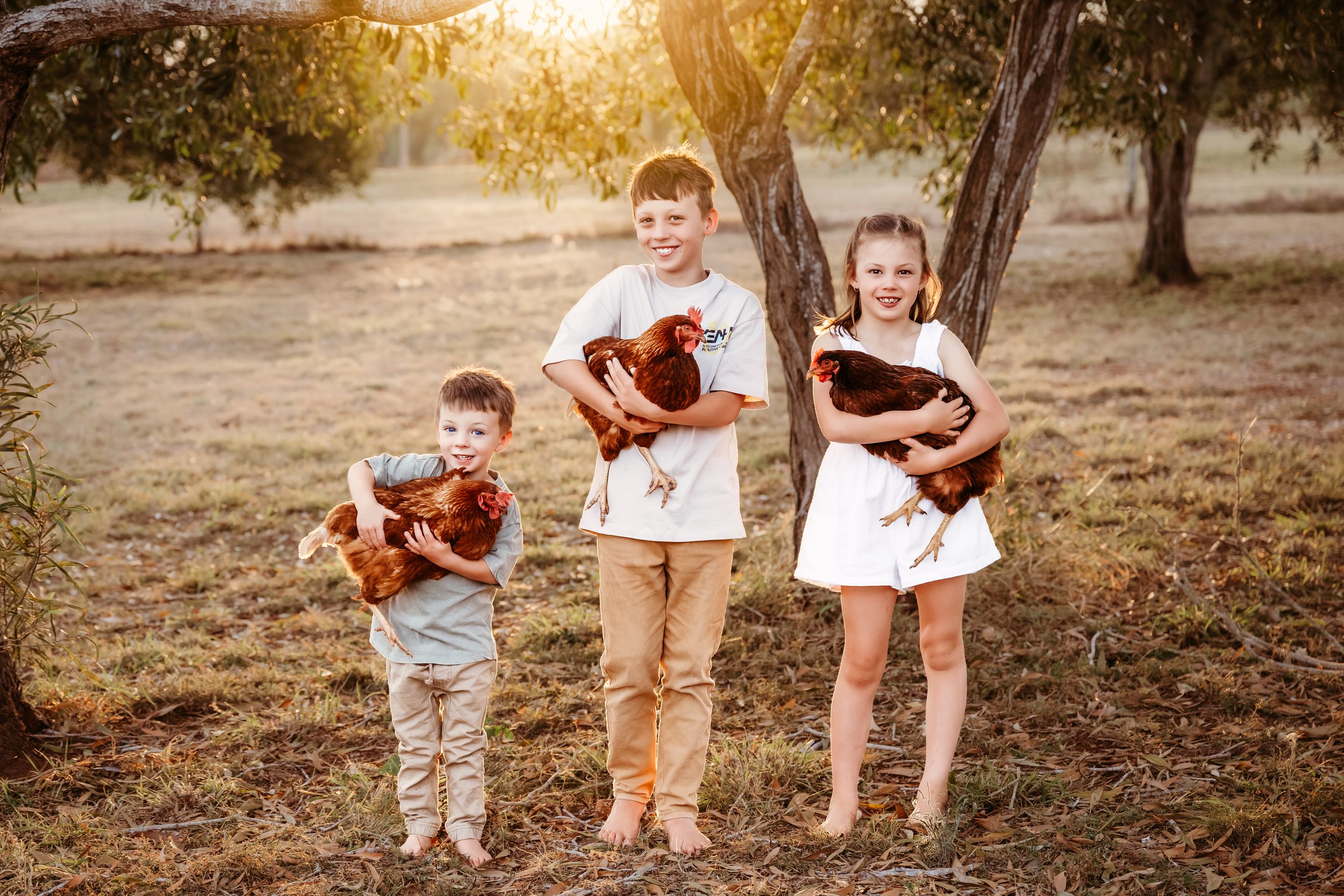 Family members walk together on a grassy path during golden hour in autumn.