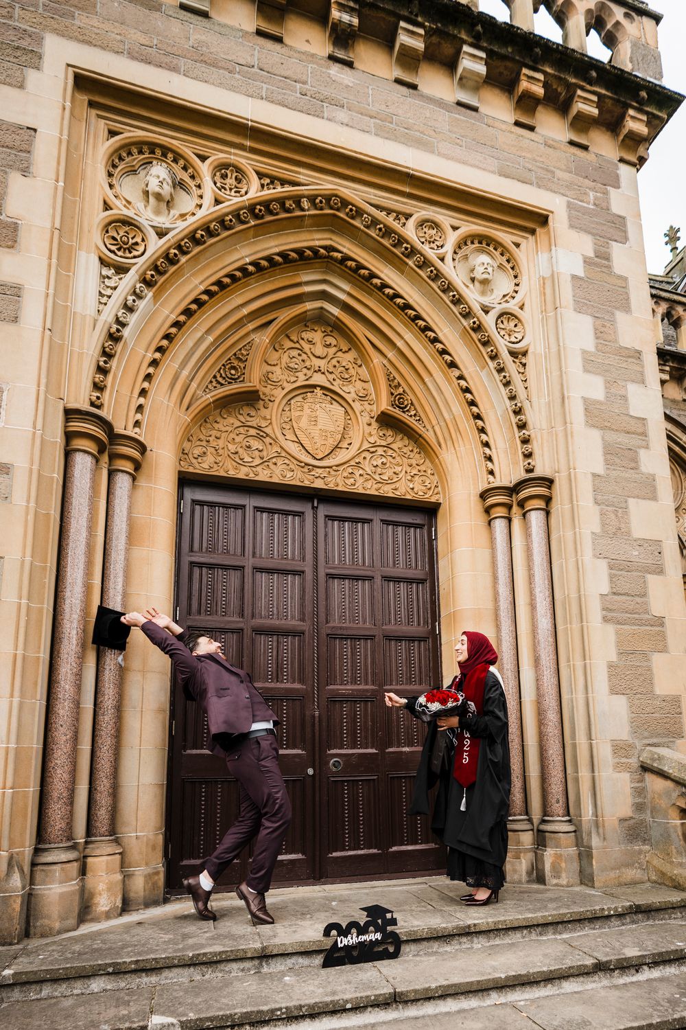 Natural graduation photo at McManus gallery Dundee with man catching graduate's cap