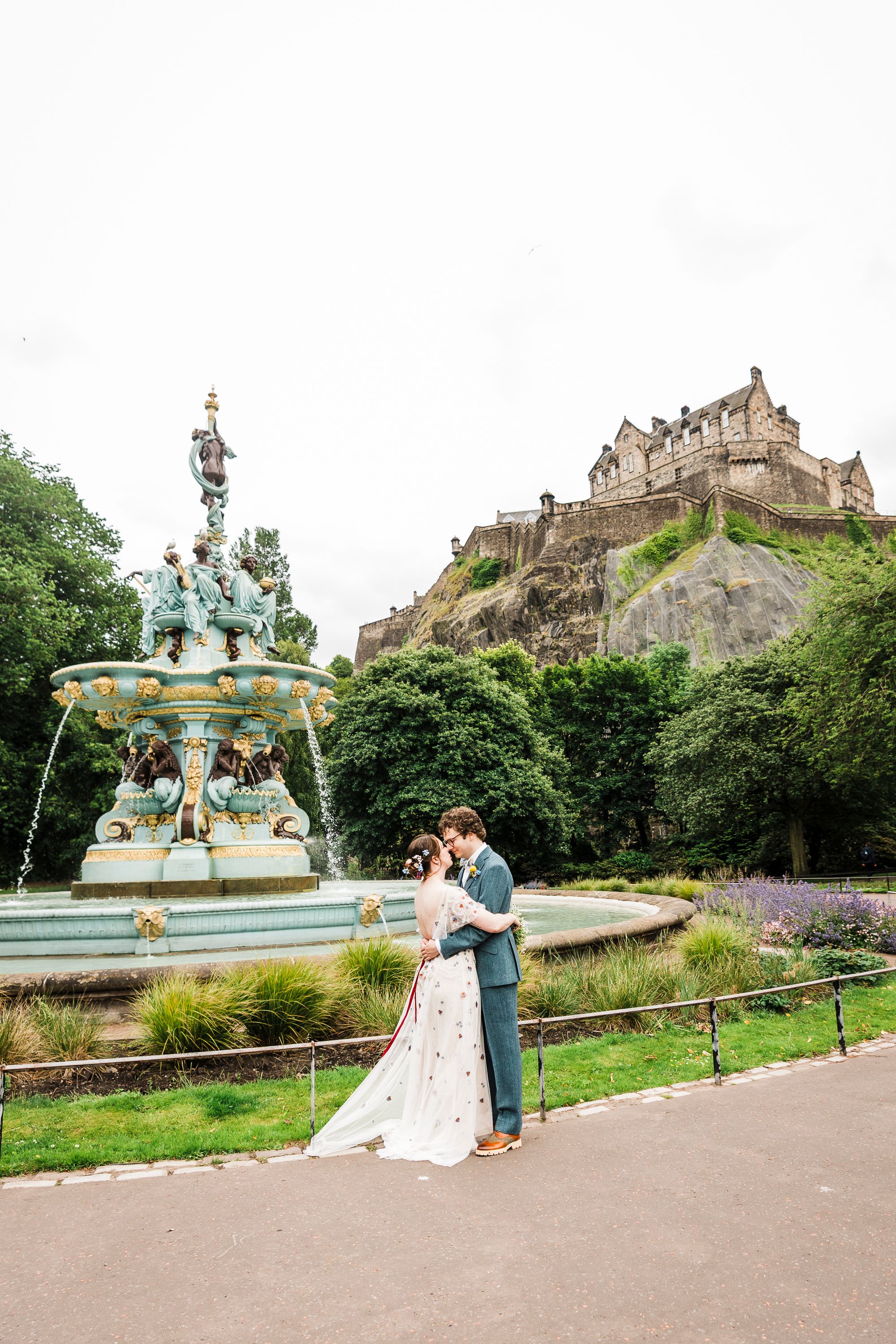 Wedding photography of bride and groom at princes street garden fountain with Edinburgh Castle in the background
