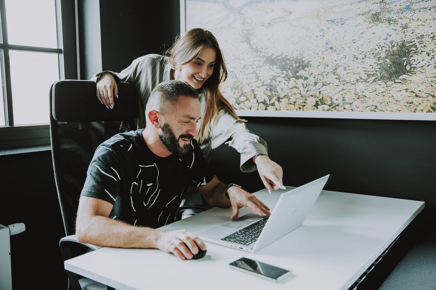 Two coworkers reviewing documents together at desk in modern office.