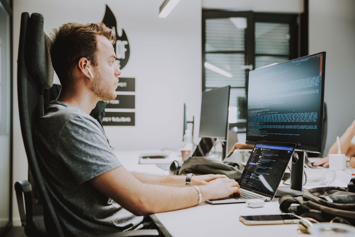 Professional working at multi-monitor computer setup in modern office environment.