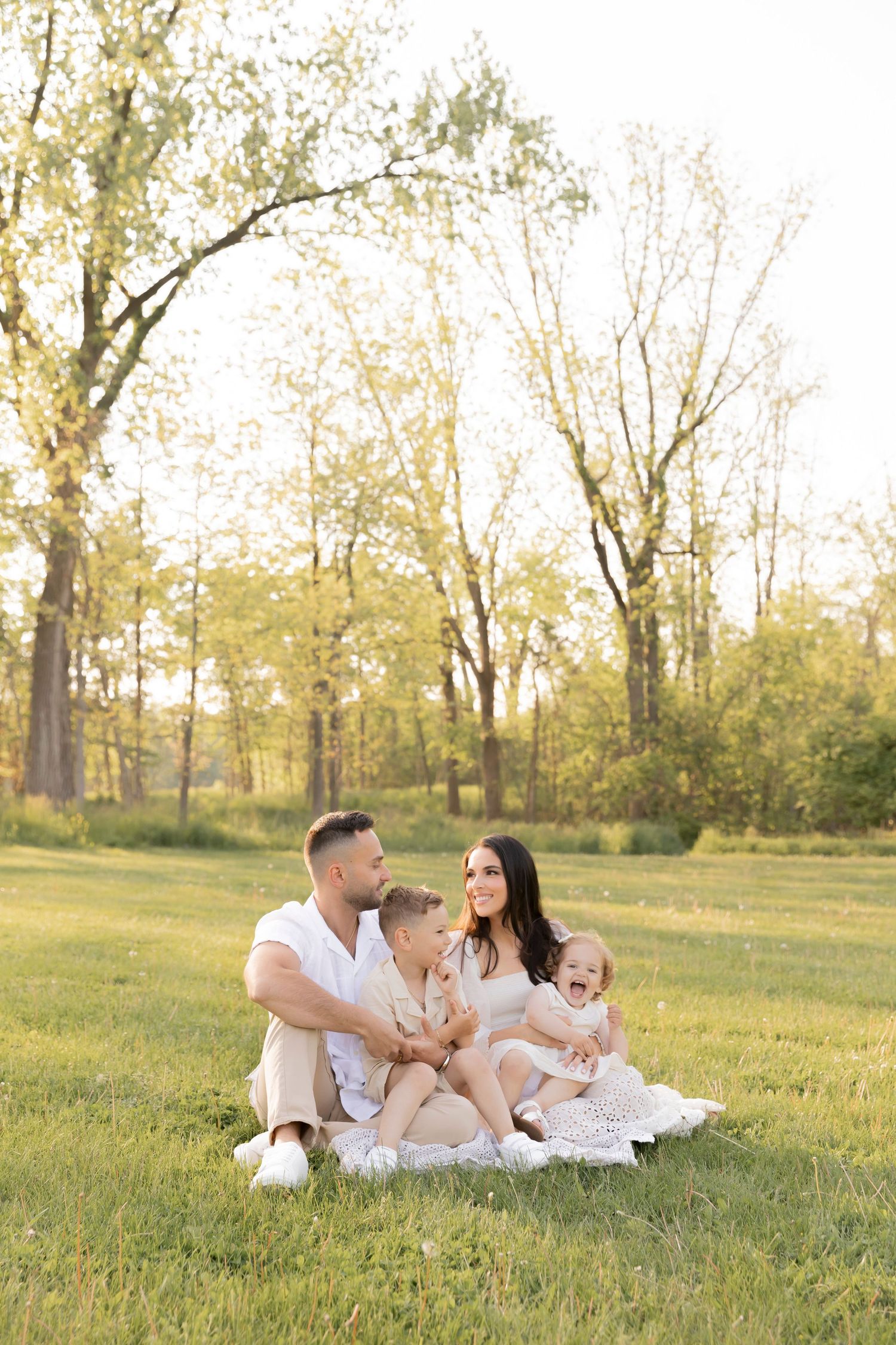 family of four with two toddler sitting on a blanket at a park in Rochester michigan