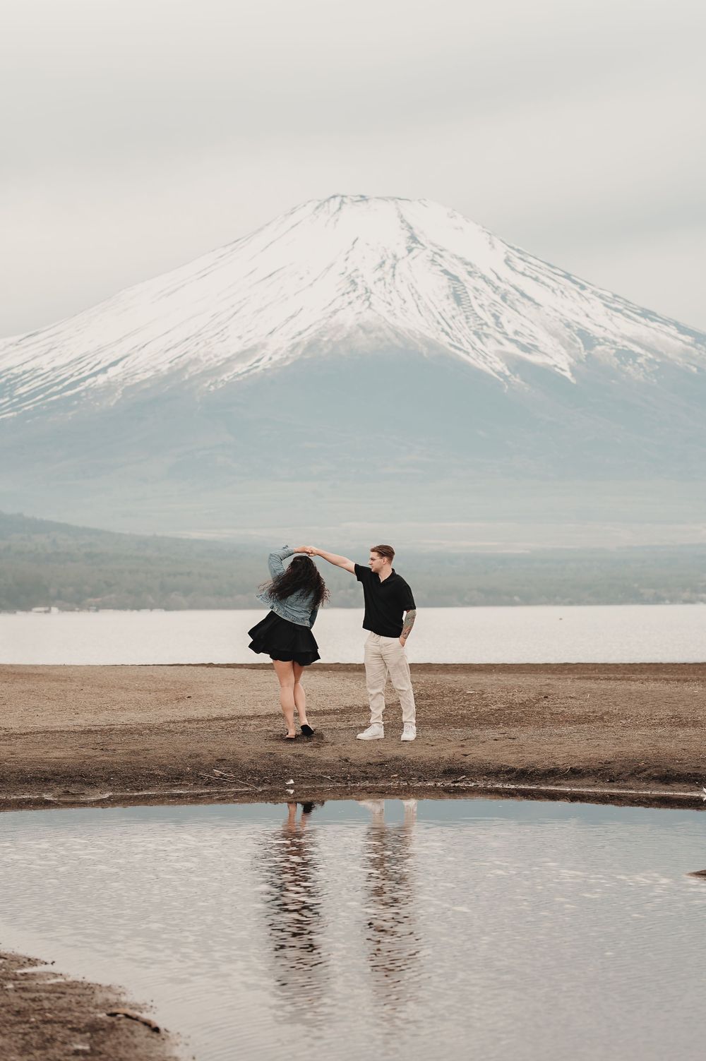 A couple enjoys a romantic moment against the stunning backdrop of snow-capped Mount Fuji in Japan.