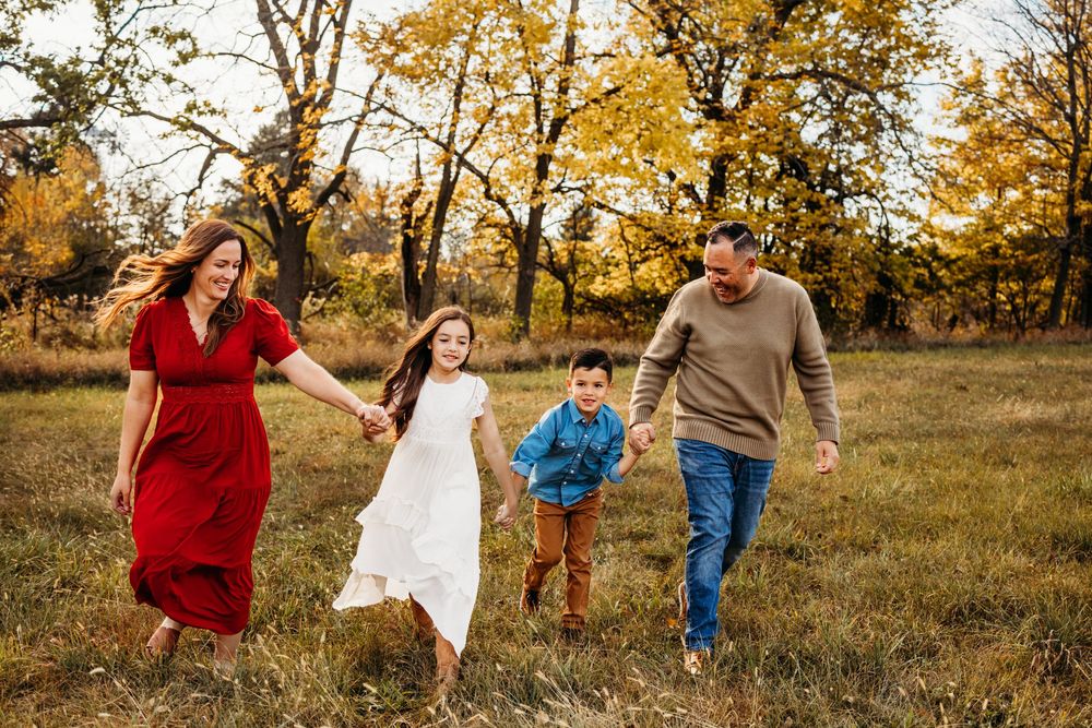 A family plays together in a golden autumn field during sunset creating a joyful outdoor scene.