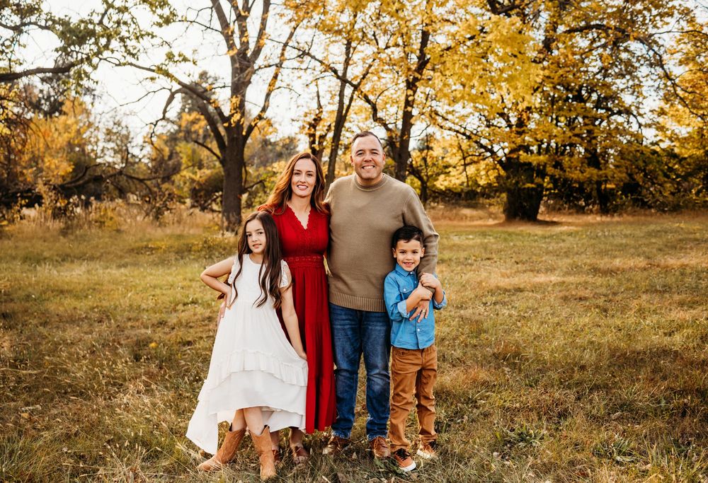 A group enjoys a warm autumn day together in a golden field with trees during sunset.