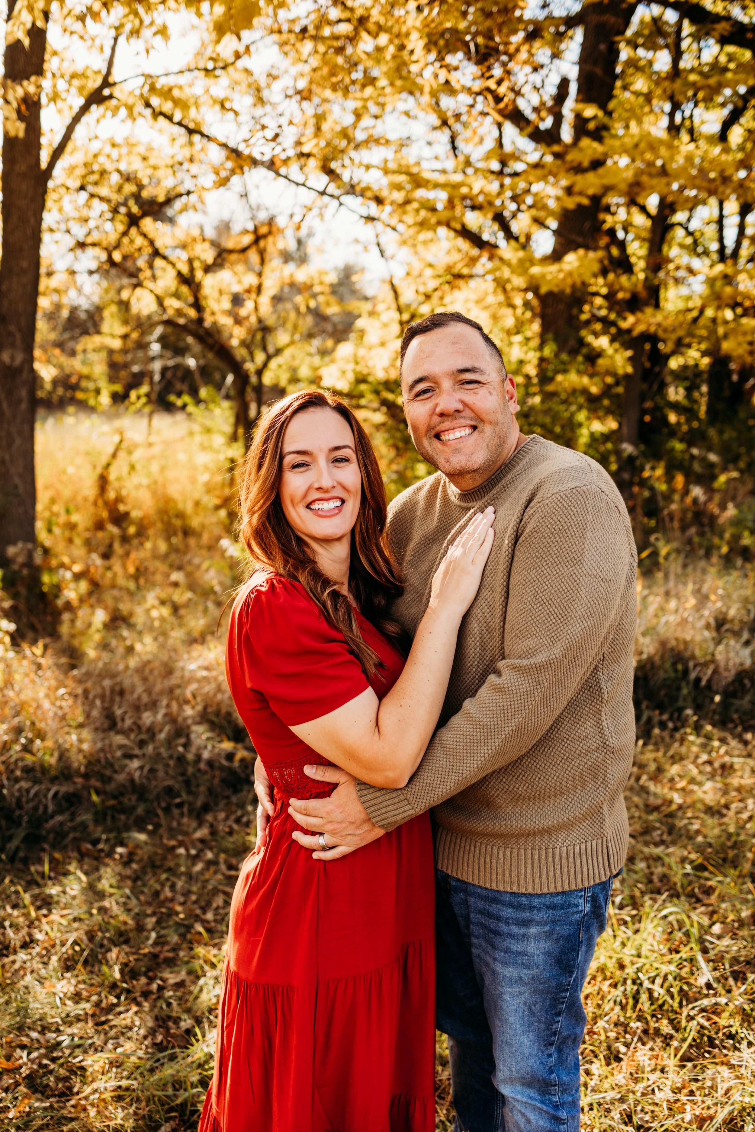 Couple laughing together in a golden autumn field during sunset photoshoot.