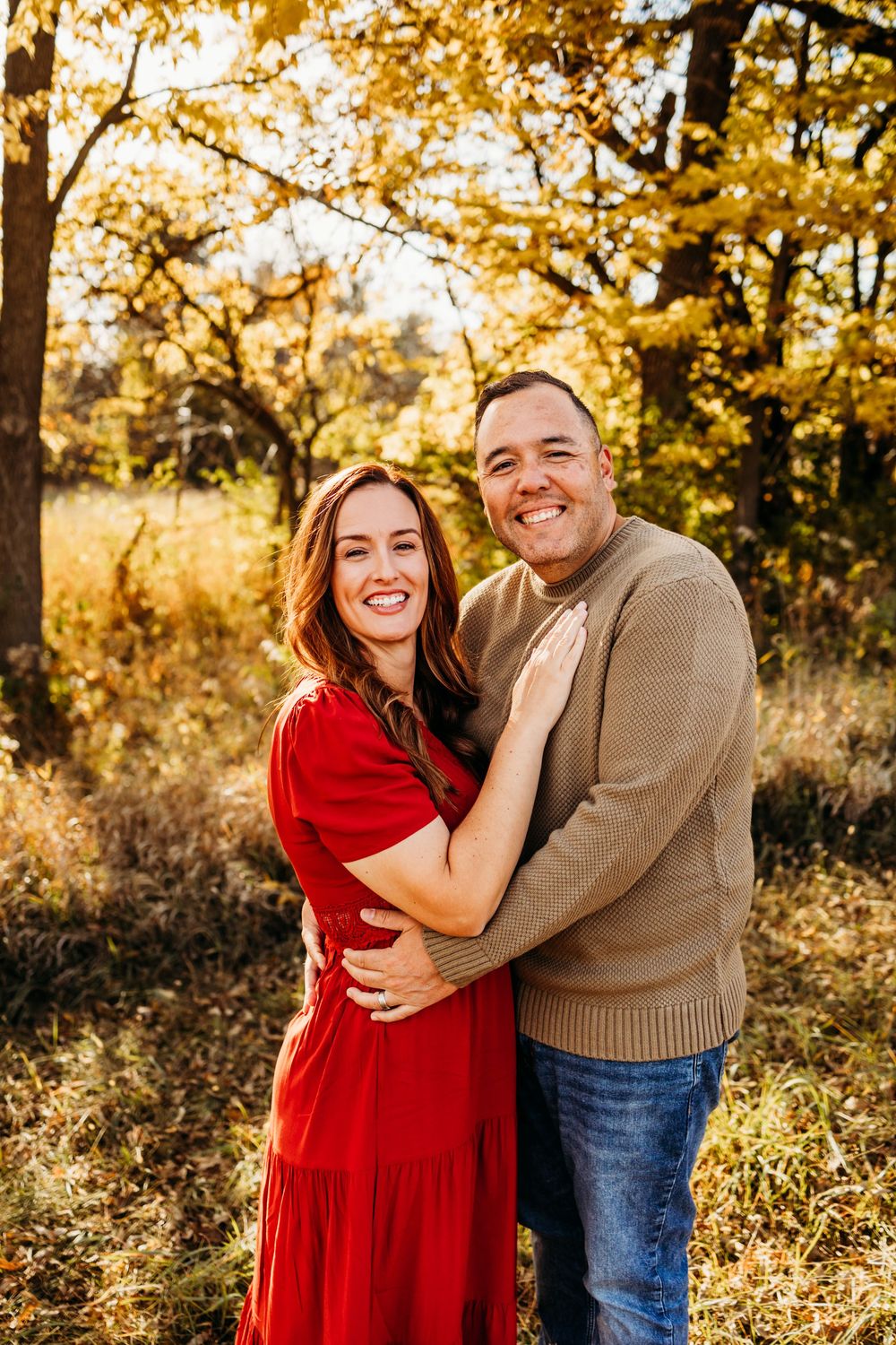 Couple laughing together in a golden autumn field during sunset photoshoot.