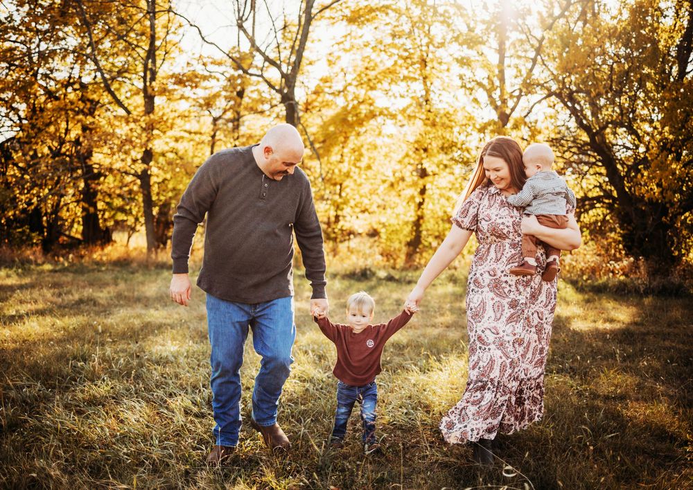 Family enjoying playful moments together in a sunlit autumn field.