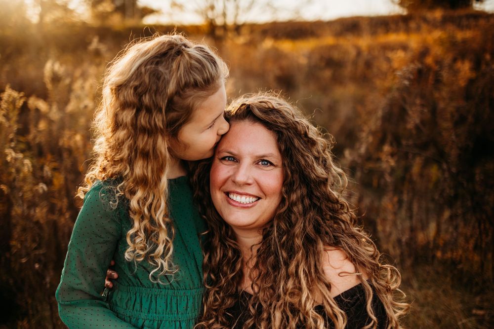 Two people share a tender moment while laughing together in warm sunset lighting.